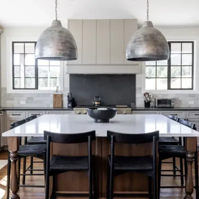 A renovated kitchen with a stone island, pendant lighting, and custom cabinetry.