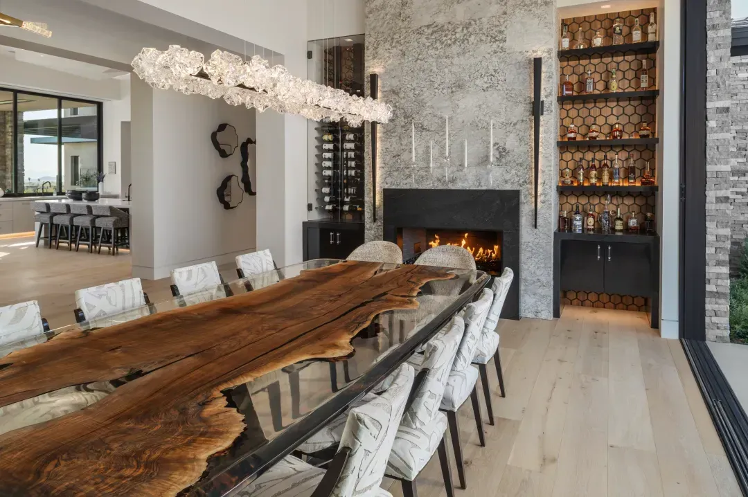 A dining room with a live-edge table, sculptural lighting, and a stone fireplace.